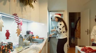 Asyalı ve beyaz kadınlar dekore edilmiş mutfakta birlikte yemek hazırlıyorlar, gülerken esrar ve karıştırıyorlar.,