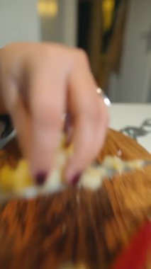 Bulanık, yakın plan beyaz kadın tahta tahtada patates doğruyor, hızlı el hareketi, sıradan mutfak ritmi, salata parçaları hazırlıyor.