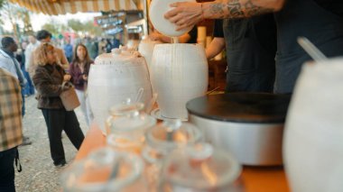 İşlek market müşterilere buharlı krep, tezgahta porselen kavanozlar, canlı meydanda alışveriş kuyruğu servis ediyor.