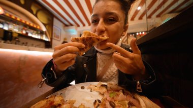 Genç bir kadın pizzayı yüzüne yakın tutarken neşeli bir ifade takınıyor, yakın plan portre, gülümseme, peynir...