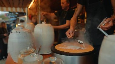 Beyaz satıcı dışarıda seramik kavanozlarla nitrojen dondurması yapıyor, buhar yükseliyor, aşçı hamur topluyor ve eğlendiriyor.