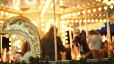 Akşam atlıkarınca ışıkları ön planda süslü atlar, çelenkler ve kurdeleler süren aile buluşmasını ön plana çıkarıyor, sıcak bokeh ve nostaljik