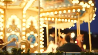 Akşam atlıkarınca ışıltısı gösterileri altın sarısı atlar ve gülümseyen sürücüler, dekorasyon ve çelenkler ön planda sıcak bir festival oluşturur.