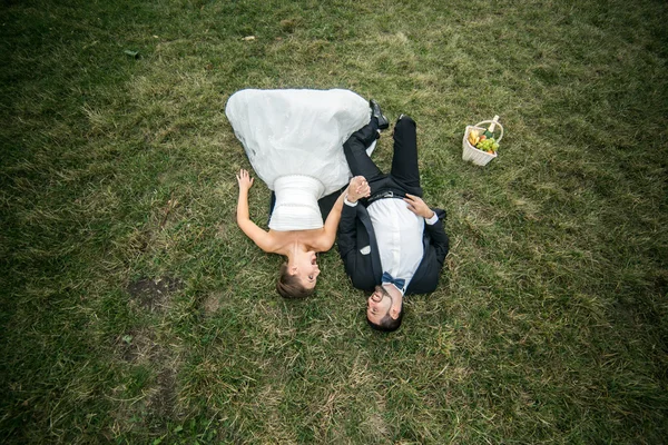 Pareja de boda acostada en la hierba — Foto de Stock