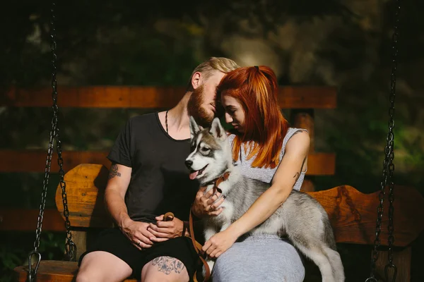 Vackra par tillsammans med hunden på en gunga — Stockfoto