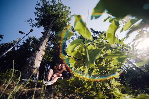 Vackra paret sitter i en skog nära trädet — Stockfoto