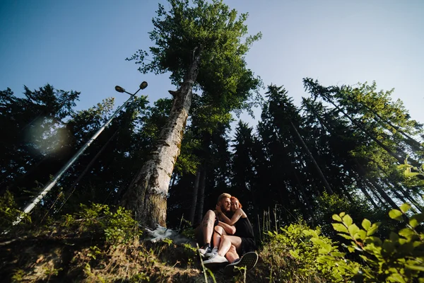 Hermosa pareja sentada en un bosque cerca del árbol —  Fotos de Stock