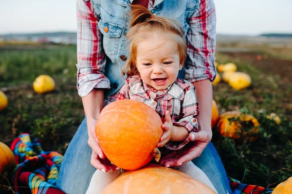 Mother and daughter sitting on pumpkins — Stock Photo, Image