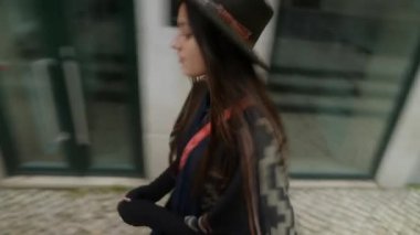 Beyaz şapkalı beyaz kadın, yakın çekim profil fotoğrafı, uzun saç ve desenli ceketi renkli yanından geçerken yakalıyor.