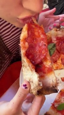 Beyaz kız esnek mozzarellayı çekiyor, uzun peynir teli, kapalı ağız ve parmaklar, parlak pepperonili üst, yapışkan erimiş