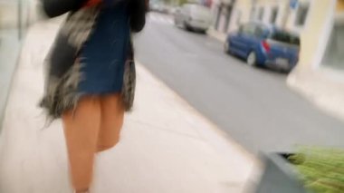 Sarı heykelin yanında yürüyen bir kadın telefon, desenli şallar, güneşli cadde, neşeli şehir arkaplanı, neşeli gezinti