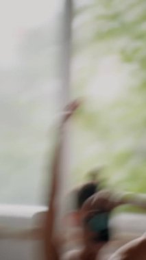 Beyaz kadın pencerenin kenarında oturmuş kendi portresini çekiyor, bulanık ayna kamerası, yumuşak sabah ışığı, rahat yatak odası, iç gözlem havası.,