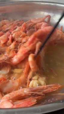 Sarımsaklı tereyağında cızırdayan karidesler, sıcak tavaya atılmış parlak mercan kabukları, buhar ve altın sos, yakın çekim aşçı tarzı aşçılık.,