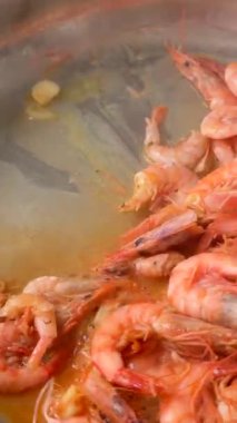 Şef karidesleri cızırdayan tavaya atar, mercan kabukları sarımsak ve tereyağı köpüğü gibi parlar, maşaları karıştırır, buhar çıkarır ve cezbeder.