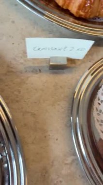 Böğürtlen fıstıklı parlak spiral hamur işleri, sıcak kafe ışığı altında gümüş tepside sergileniyor, narin kabuklu karamelize edilmiş kabuk.