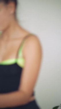 Elbiseye parlak zincirli aksesuar ekleyen kadın, neon kaplamalı kesim bluzu içinde elleri ve gövdesini kapatan, samimi ışıltı tasarımı