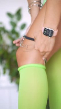 El tokaları bağlandıkça neon çorabın üzerine sarılı kalça zinciri, cilde yakın çekim ve metalik ışıltılı şehvetli hazırlık.