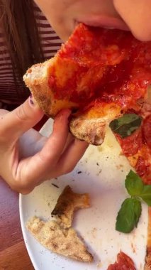 Kafkasyalı çocuk büyük domates sosu ısırıyor, ağız ve kabuğu kapatıyor, açık hava kahvesi, pepperoni ve fesleğen yiyor.