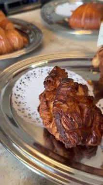 Fıstıklı çikolata kıvrımları, parlak jöleli örülmüş düğüm şekilleri, ezilmiş fındıklar serpiştirilmiş tepside, derin karamelize edilmiş.