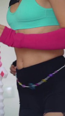 Beyaz etkileyicisi vücut hareketleri, turkuaz spor sutyeni ve şort heykeli, danslı karın kasları eğitimi gösteriyor.