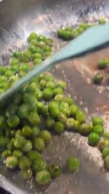 Spatulanın altında fokurdayan yeşil biberler içerik yaratıcısı tarafından hızlı bir şekilde harekete geçirilmiş, canlı bir şekilde fırlatılmış ve el kamerası ile yakın çekim yapılmış.