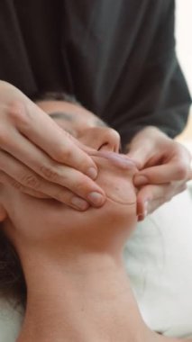 Klinisyen şekillendirme çene hattı çimdikleme ve gevşetme, çene ve çene üzerinde detaylı yakın çekim, odaklanmış eller, temiz stüdyo ışığı ve sakin