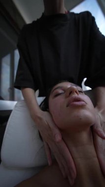 Panoramik pencere ışığıyla kentsel spa boynu ritüeli uygulayan, boyun ve omuzlara uzun yatıştırıcı darbeler uygulayan, yaslanan