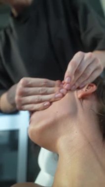 Yakın plan beyaz kadın lenfatik drenaj yüz, estetisyen çene ve boyun boyunca hafif ritmik darbeler kullanıyor