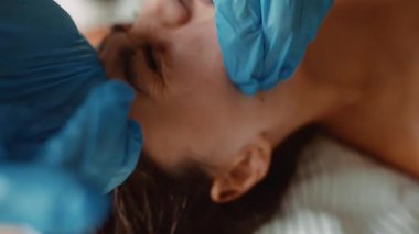 Yakından yanak çıkarma pratisyeni eldivenli parmaklar sabit basınçlı stüdyo ışıklandırmalı hasta gevşek cilt detayı