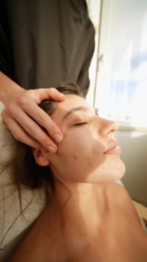 Kaş ve şakak aküpresi, şakak ve alın boyunca parmak basıncı, müşterinin yavaş nefes alması, güneş ışığı alan pencere arkası.,