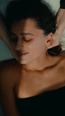 Güneş ışığı odasındaki bütünsel uygulayıcıdan hedef alınan kulak ve boyun aküpresi alan yaslanan kadın, hafif basınç noktaları