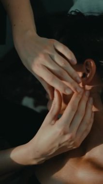 Yakın plan beyaz kadın, altın saat boyunca kulak refleksolojisi görüyor, terapist kulaklık boyunca hedeflenen parmak basıncını uyguluyor.