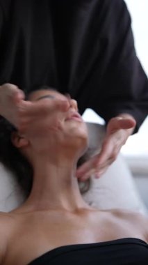 Odaklanmış lenfatik yüz drenajı, çene ve boyun boyunca hafif süpürme hareketleri kullanan pratisyen, yumuşak yaslanan istemci