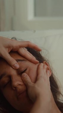 Alnından nazikçe avuç içi darbeleriyle basınç boşaltılıyor, kadın gözleri kapalı olarak uzanıyor, terapist sürekli aşağı doğru iniyor.