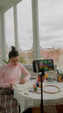 Çevrimiçi dükkan için el yapımı paketler hazırlayan genç bir kadın, paketleme paketleri etiketleme ve kurdele düzenleme, odaklanmış girişimci enerjisi, küçük