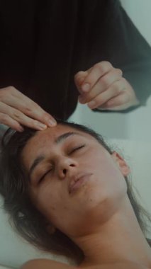 Hedef alınlı gerilim terapisi. Alnına ve kaşına parmak basma uyguluyor. Kadın tedavide sakin yatıyor.