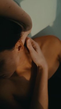 Parlak stüdyoda kulaklık masajı sekansı alan yaslanmış bir kadın. Terapist baş parmak basıncı ve hafif kaldırma kullanıyor.