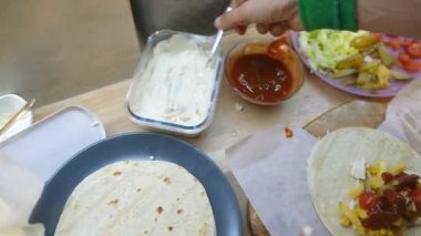 Tortilla sosu ve sebze parşömeniyle yuvarlanan ve mühürlenen eller, kutu gecikme mutfağı için hazır.