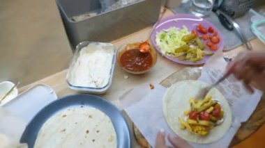 Tortilla ambalajına baharat ve sos ekleyerek mutfak sahnesine son rötuşu yapıyor.