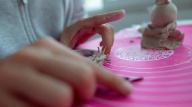 Pembe hasırın üzerinde hamur kabuğu oluşturan eller, arka planda hamur parçaları, nazik parmak ucu şekillendirme, ışık.