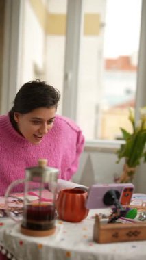 Pencerede zaferi kutlayan bir kadın, kollarını kaldırıyor, gülümsüyor, aksesuarlara uzanıyor, hayat dolu bir an.