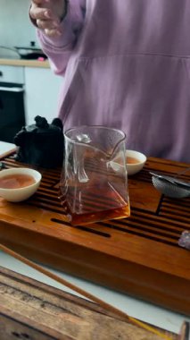 Tütsülenmiş tütsü ve buharlı fincanla ahşap tahtada duran lavanta kapüşonlu bir kadın meditasyon atmosferi yaratıyor.