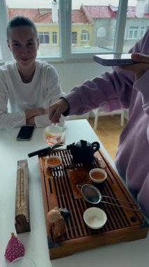 Tahta çay tahtasında porselen bardağa doldur, odaklanmış el tekniği ve zarif akış, sakin bir şekilde vurgulanan teknik.