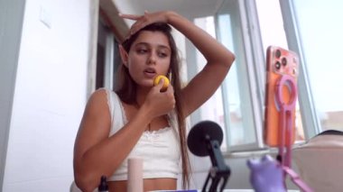 Balkonda balkon testi yapan genç bir kadın sünger, elf kulakları aksesuar, telefon standa bağlı ve mikrofon aktif.,