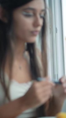 Genç Asyalı kadın kesin göz kalemi kullanıyor, beyaz grafik kalemi, pamuk bezi temizleme, sakin konsantrasyon, pencere kibri, modern