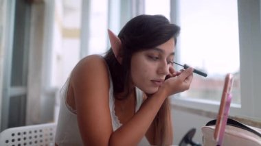 Elf kadın pudra cilalıyor ve güneş ışığı altında allık sürüyor gösteriş, şakacı yumuşak yumuşak puflar, yumuşak doğal bitiş ve sıcak