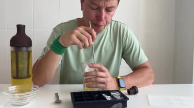 Tat testi, konsantre ifade ve buz küpleri, çatal bıçak ve şişe için camda hareketli duran beyaz adam.