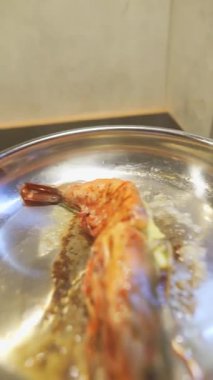 Limonla kaplanmış tereyağlı karides, mavi eldivenli beyaz şef kabuğun üzerine narenciye sıkar, cızırdayan yağ ve kaynayan sarımsak,