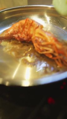 Makro yakın plan karides kafası ve sarımsak, arka planda görünen beyaz şef tekniği, kaynayan yağ ve kahverengi karamelizasyon,