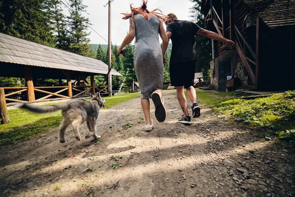 Casal corre na estrada na natureza com o cão — Fotografia de Stock